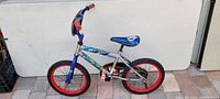 Full view of the 12 inch Huffy Avenger kids bike with red rims, blue and silver frame, and themed seat.