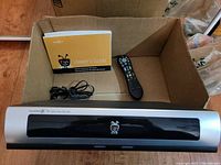TiVo Series 2 DVR unit, remote, power cord, and viewer's guide shown inside cardboard box, view of front and top.