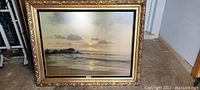 Front view of the framed print showing the twilight beach scene with a gold decorative frame.