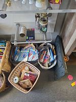 Multiple baskets filled with various art supplies including stickers, colored pencils, and crafting tools placed on floor under glass table.