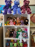 Full view of shelf showing numerous plush toys including multiple Beanie Babies and large plush bears on the top shelf.