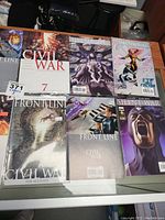 Photo showing 7 comic books laid out, including Civil War issues 7 and 5, Front Line issues, and Silent War.