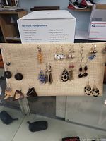 Fabric earrings holder displaying assorted costume earrings in different styles and colors.
