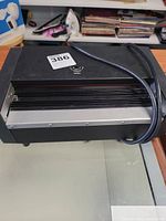 Front view of black Laminator 6000 with laminating slot and power cord on top.