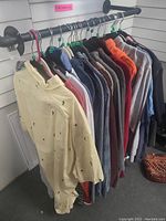 Photo of 12 men's extra large shirts and tops hanging on a rod, showing a range of colors and types including button-ups and T-shirts