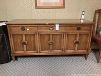 Front view of the wooden buffet showing drawers, doors, and legs.