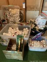 View of several plastic bins with white and red Christmas ball ornaments, battery candles in original box, and white craft decorations in a cardboard box.
