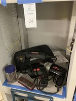 Photo showing two electric drills, a black variable speed multi-tool case, and a jar of drill bits on a shelf.