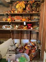 Wide view of multiple shelves with fall decor items including silk flowers, artificial pumpkins, and harvest signs.