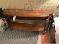 Front view of wood foyer table showing curved shape, carved legs, and lower shelf