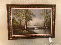 Full front image of the framed oil painting showing trees near water body with a misty background
