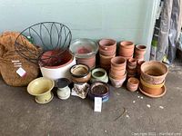 Wide view showing assorted garden pots including clay, ceramic, glass dish, hanging basket frame, and coco liners.