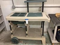 Full side angle showing entire wheeled gardening cart, large wheels, and lower grid shelf with open slats.