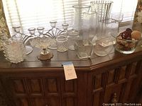 Full view of the glassware lot including dishes, decorative jars, tall vases, and a glass bowl with decorative balls