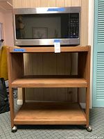 Microwave resting on wooden cart showing overall setup and measurements below each item