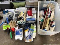Overall image showing assorted painting supplies including brushes, rollers, paint pans, and paint guards organized in bins and containers.