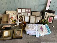 Wide view of the collection showing picture frames, candles, brass holders, linens, and wreaths arranged on floor