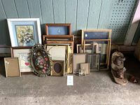 Wide shot showing collection of picture frames, flower painting in white frame, and carved dog wall hooks