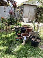 Wide view of assorted garden items including pots, plant stands, and wind chimes in outdoor yard setting