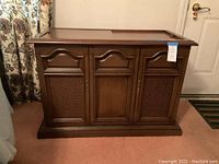 Front view of the wooden cabinet showing closed paneled doors with decorative designs.