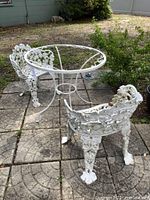 Full view of wrought iron table and two chairs set on patio, showing overall condition and missing glass top