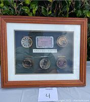 Framed display showing 5 faux fly fishing reels and a vintage Ohio fishing license with label inside the frame.