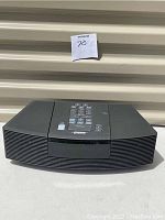 Front angle view of black Bose Wave radio with curved speaker grille and keypad control on top, showing moderate surface wear.