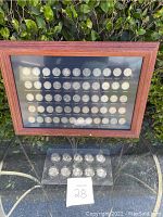 Front view of two wooden framed display cases with state quarters and a plastic holder with additional quarters in front.