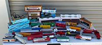 Overview photo of entire lot showing varied boxed and loose HO scale model trains including engines and cars laid out on a table.
