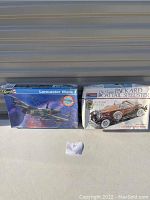 Photo of Revell Lancaster Mark I model airplane kit box and Monogram 1933 Packard Boattail Speedster model car kit box side by side on concrete floor.