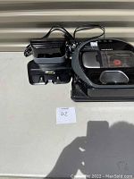 Photo of Samsung Powerbot vacuum cleaner and charging dock with cords, showing overall lot contents and setup.