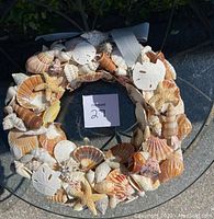 Top view of the handmade sea shell wreath showing the variety and arrangement of shells and starfish on a circular base.