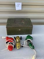 Vintage slot car with two wired controllers and green metal storage box on a table.
