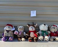 Front view of five Starbucks Bearista plush bears lined up showing various seasonal costumes and tags.