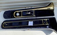 Trombone inside the hard case showing the full instrument layout with slide extended, mouthpiece, and case lining.