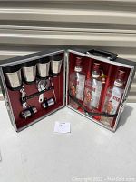 Portable bar case open to show inside components including drinking cups and liquor bottles