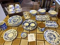 Full lot display showcasing various blue and white ceramic dishes, bowls, plates, butter dishes, salt cellar, and serving trays arranged on a table.