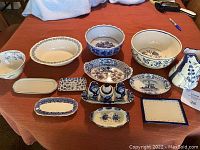 Full lot showing various blue and white bowls, trays, condiment set, and pitcher arranged on a table.