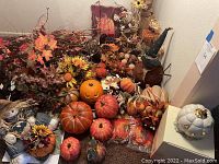 Wide view of assorted fall decorations showing artificial flowers, pumpkins, scarecrows on carpet floor