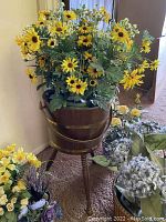 Pedestal bucket with artificial sunflowers and surrounding flower bouquets