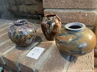 Three decorative pots arranged on stone hearth showing colors, shapes, and finishes.