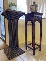 Photo of two wood plant stands with succulents on top, shown near window and on tile floor.