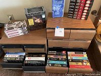 Photo showing five wooden VHS storage drawers holding multiple VHS tapes and two visible box sets including "From the Earth to the Moon".