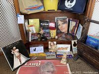 Two airline bags (Pan Am and Japan Air Lines), yellow starburst trash can, and assorted memorabilia with magazines and posters.
