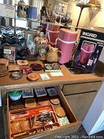 Display of vintage wine rack, Ingrid portable wine cooler in original box, bar tools, and coasters on a wooden surface and inside an open drawer