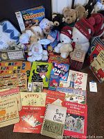 Full lot image showing assortment of stuffed animals, piano lesson books, children’s books, wooden puzzles, and boxed games.