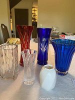 Six vintage cut crystal and glass vases including two colored vases with chips, two clear cut glass vases and one Mikasa bone china vase on table.