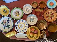 Top view showing the entire collection of Stangl pottery and mixed ceramics on a wood table with floral and fruit designs, plates, bowls, trays, and salt and pepper shakers