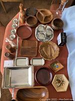 Full lot photo showing all items including carved wood bowls, trays, salt and pepper shakers, cheese board, and candle holders on table.