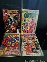 Four DC Comics comic books displayed together, showing front covers with characters like Green Lantern, The Flash, and Justice League members.